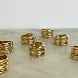 Gold rings stacked on a marble surface with a white background