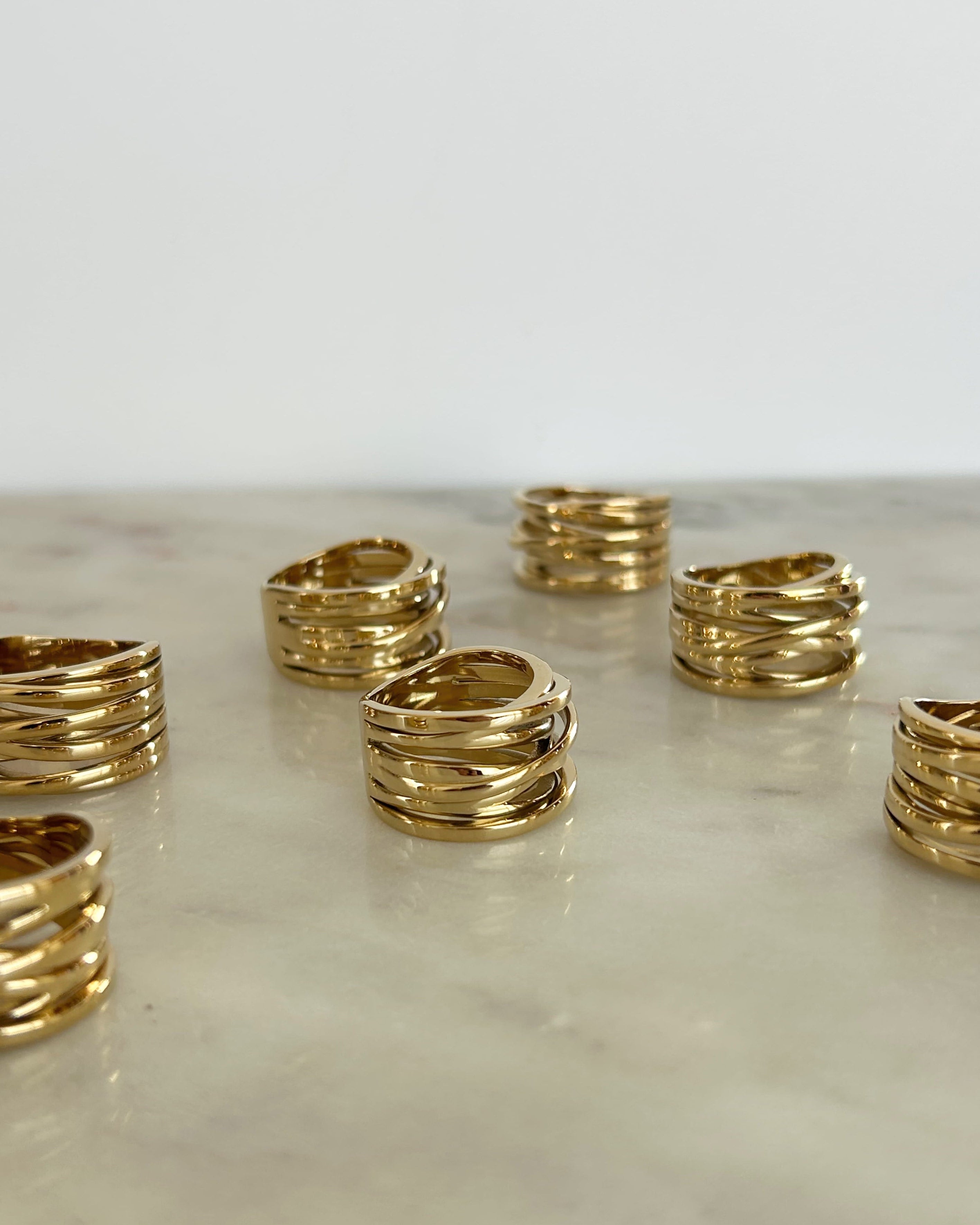 Gold rings stacked on a marble surface with a white background