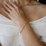 Close-up of a person wearing a gold bracelet and ring on a white background