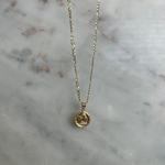 image of a gold angel pendant necklace on a marble backdrop