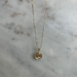 image of a gold angel pendant necklace on a marble backdrop