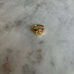 image of a gold angel signet ring on a marble table