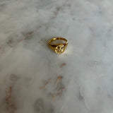 image of a gold angel signet ring on a marble table