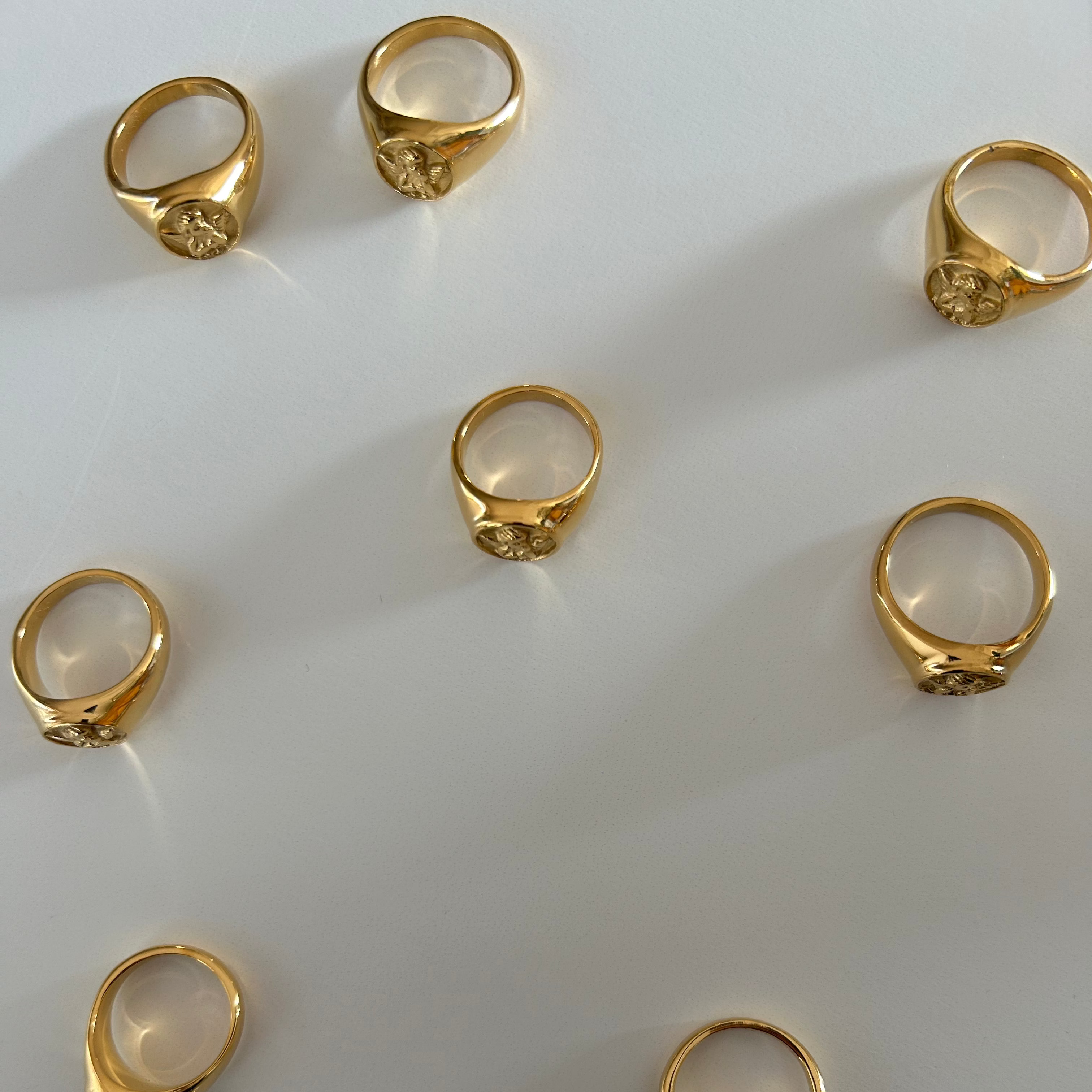image of multiple gold rings scattered on a white table