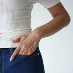 Person wearing a white ribbed top and blue jeans with a plain background