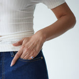 Person wearing a white ribbed top and blue jeans with a plain background