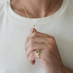 Person wearing a gold necklace and ring on a plain background