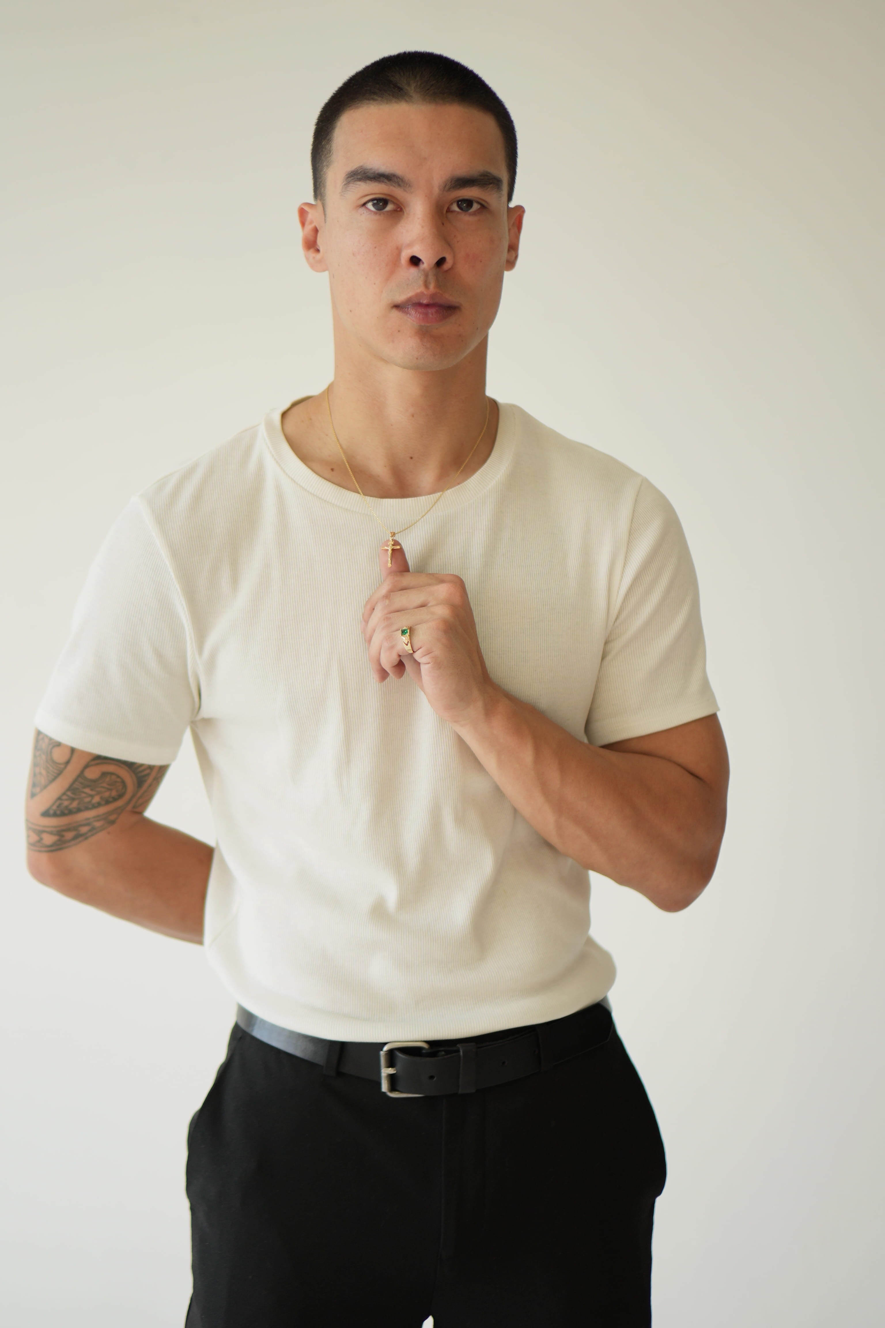 Man wearing a white t-shirt and black pants against a plain background