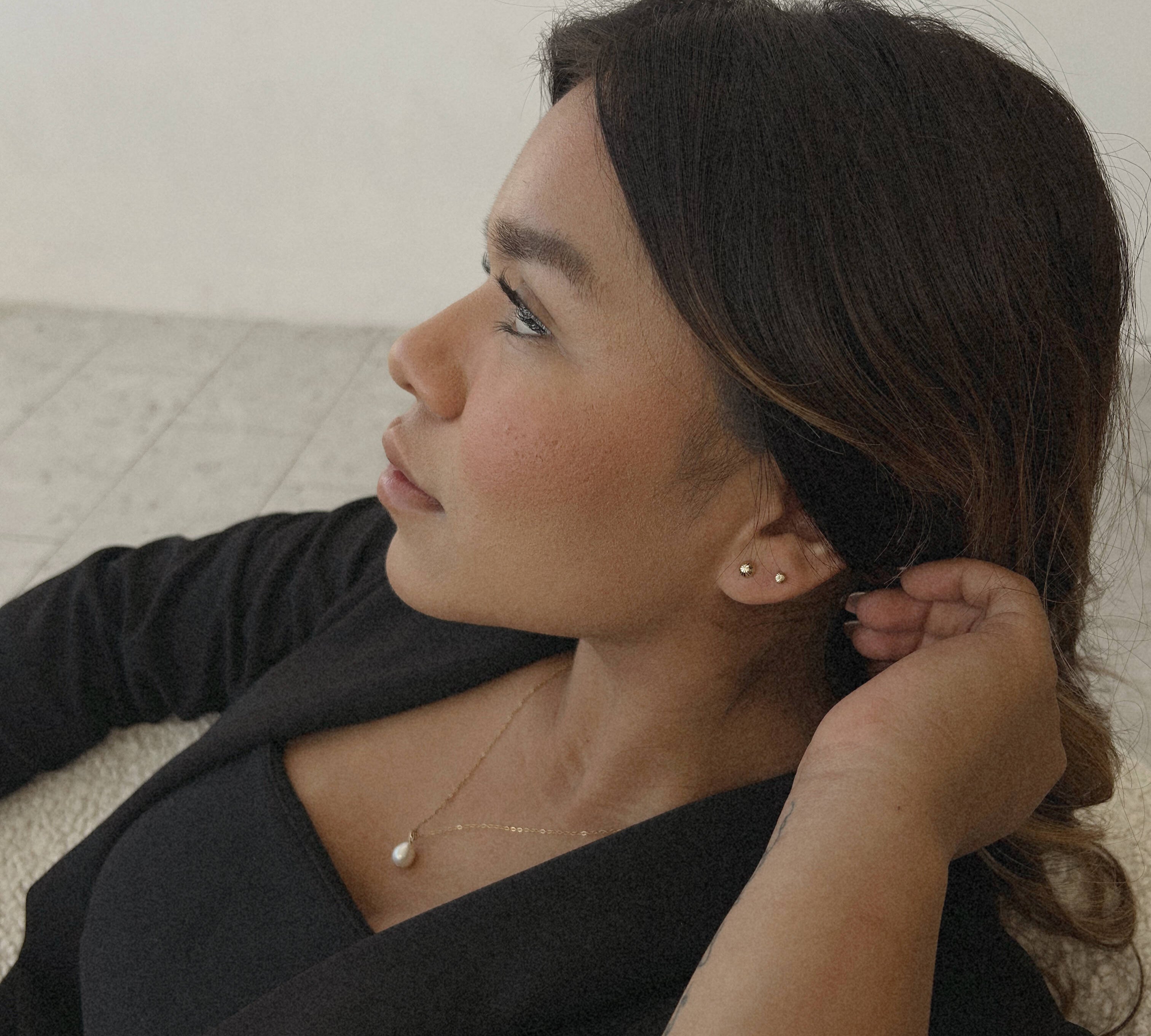 image of a woman looking to the side wearing 14k gold diamond cut gold stud earrings