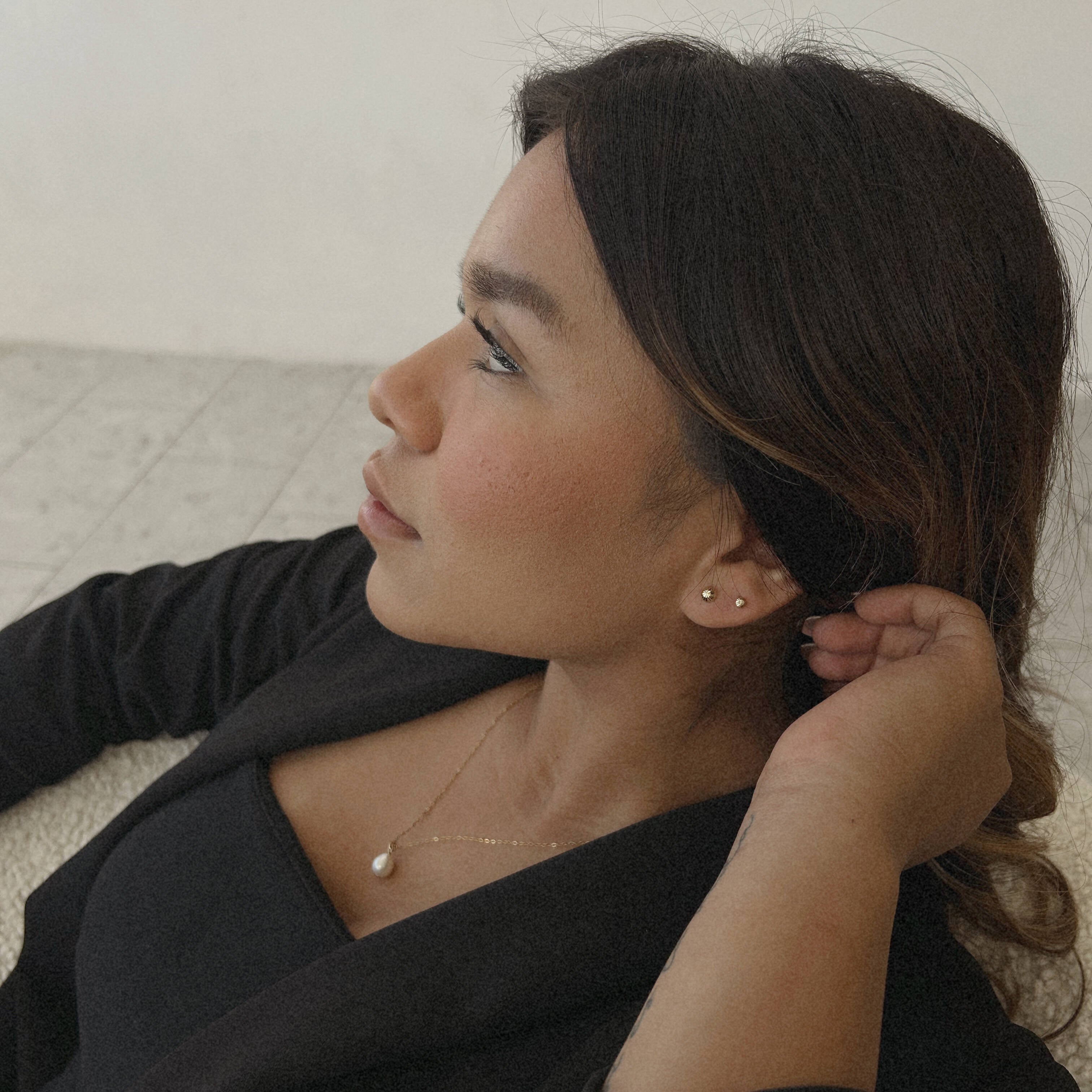 image of a woman looking to the side wearing 14k gold diamond cut gold stud earrings