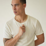 Man wearing a plain white t-shirt against a neutral background