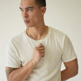 Man wearing a plain white t-shirt against a neutral background