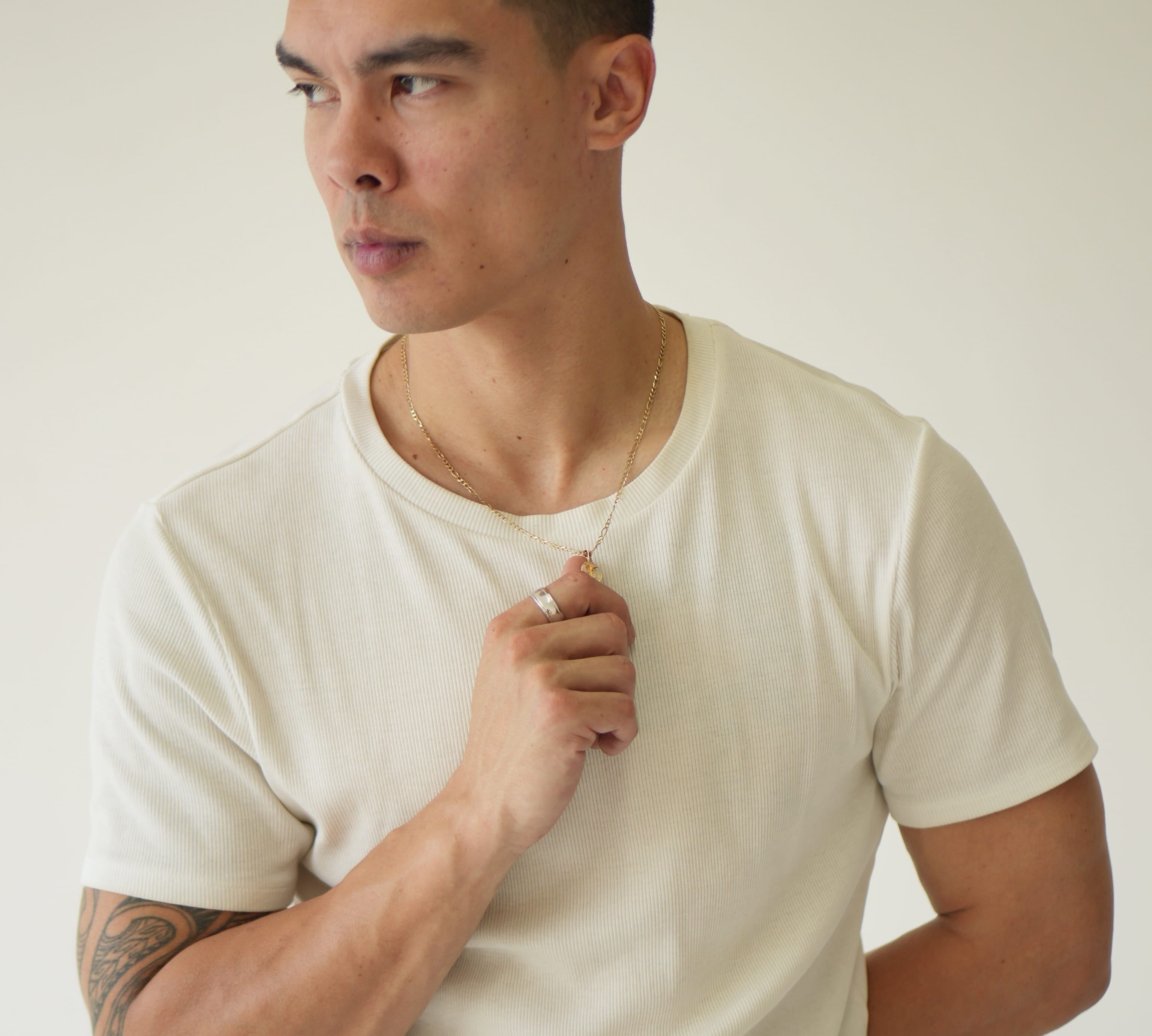 Man wearing a plain white t-shirt against a neutral background