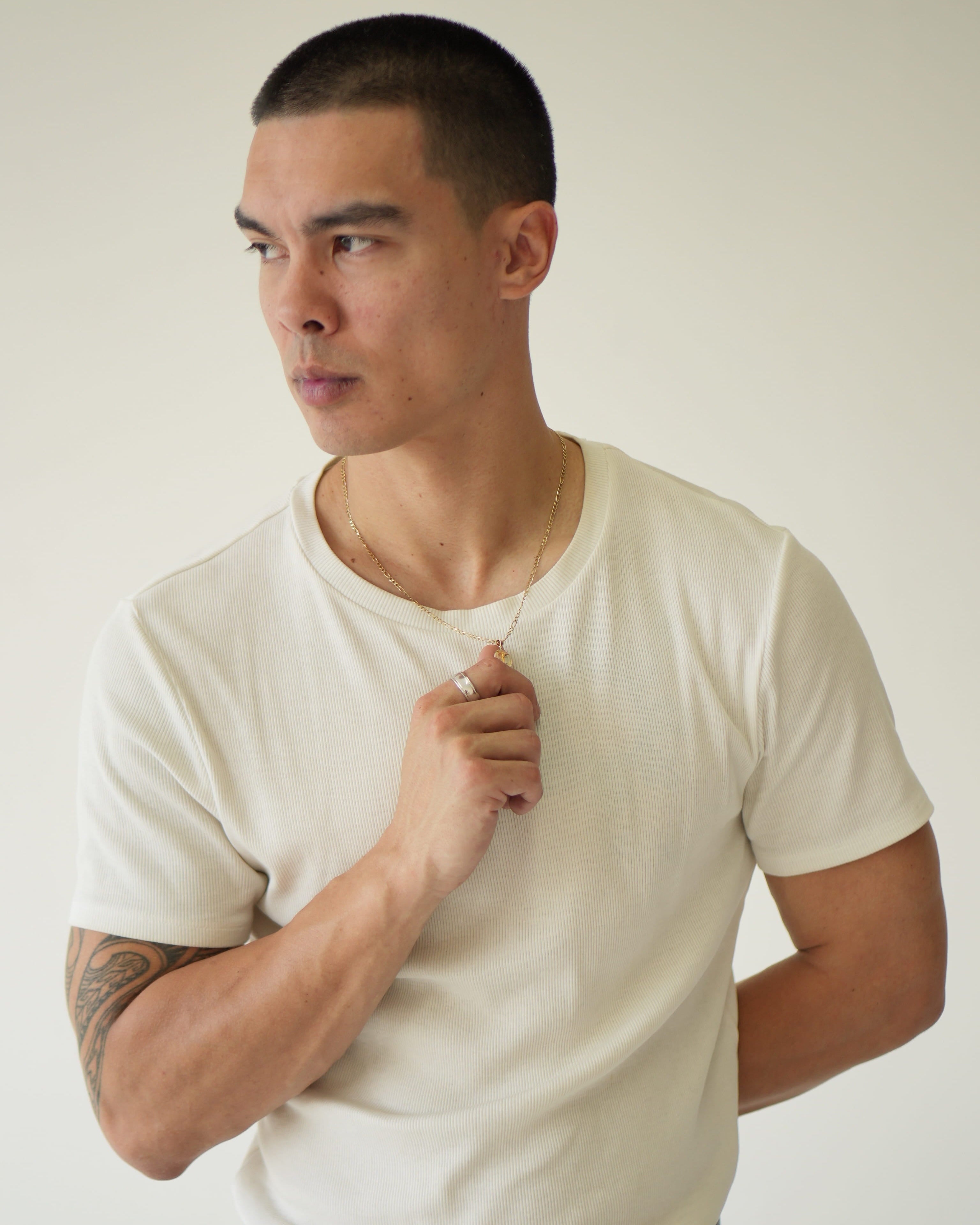 Man wearing a plain white t-shirt against a neutral background