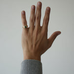 Hand wearing a ring with a plain background