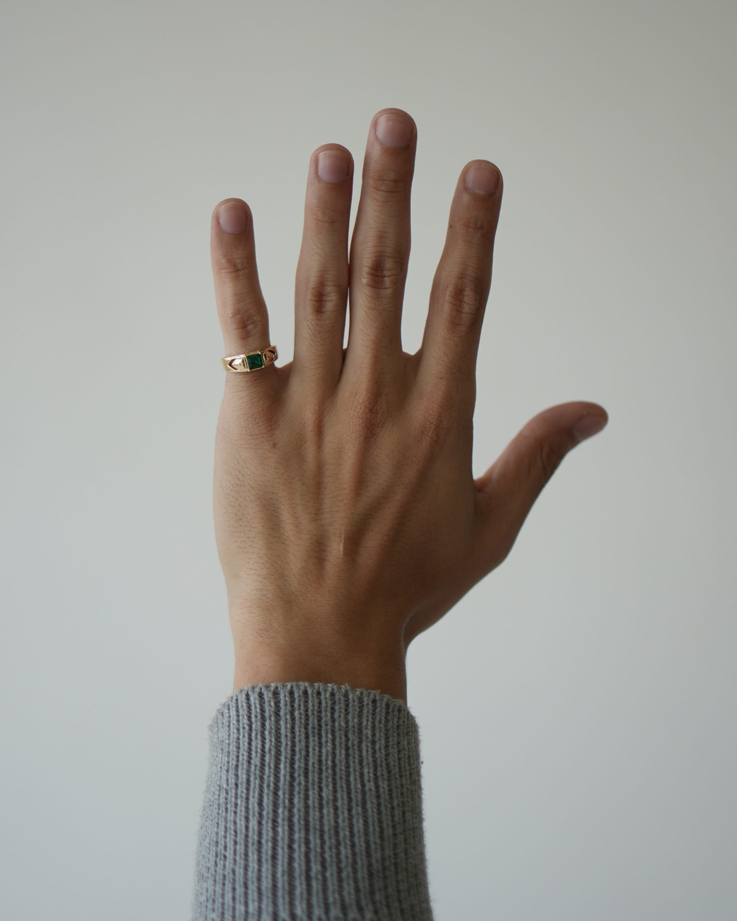 Hand wearing a ring with a plain background