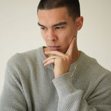 Man wearing a gray sweater with a neutral background