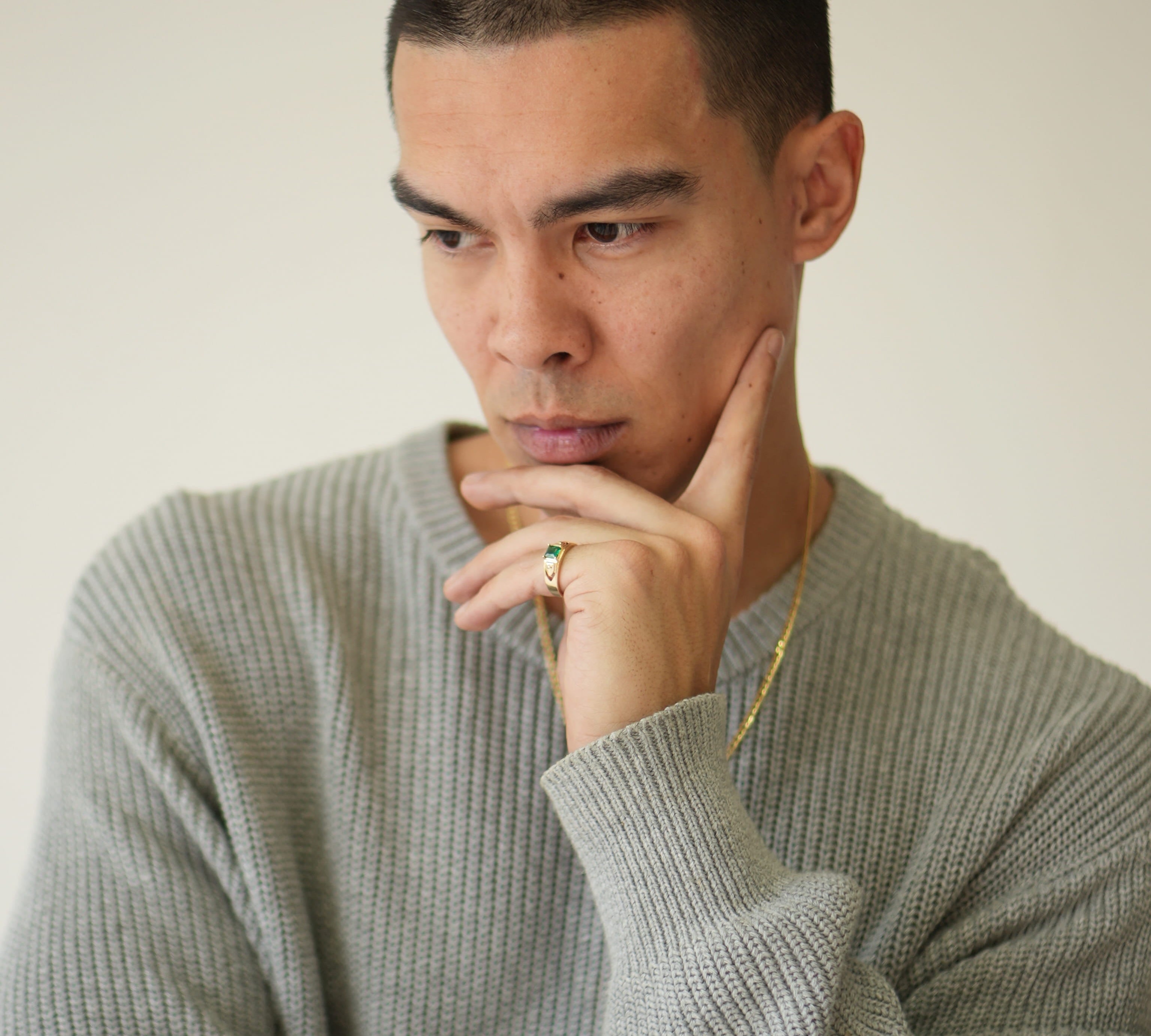 Man wearing a gray sweater with a neutral background