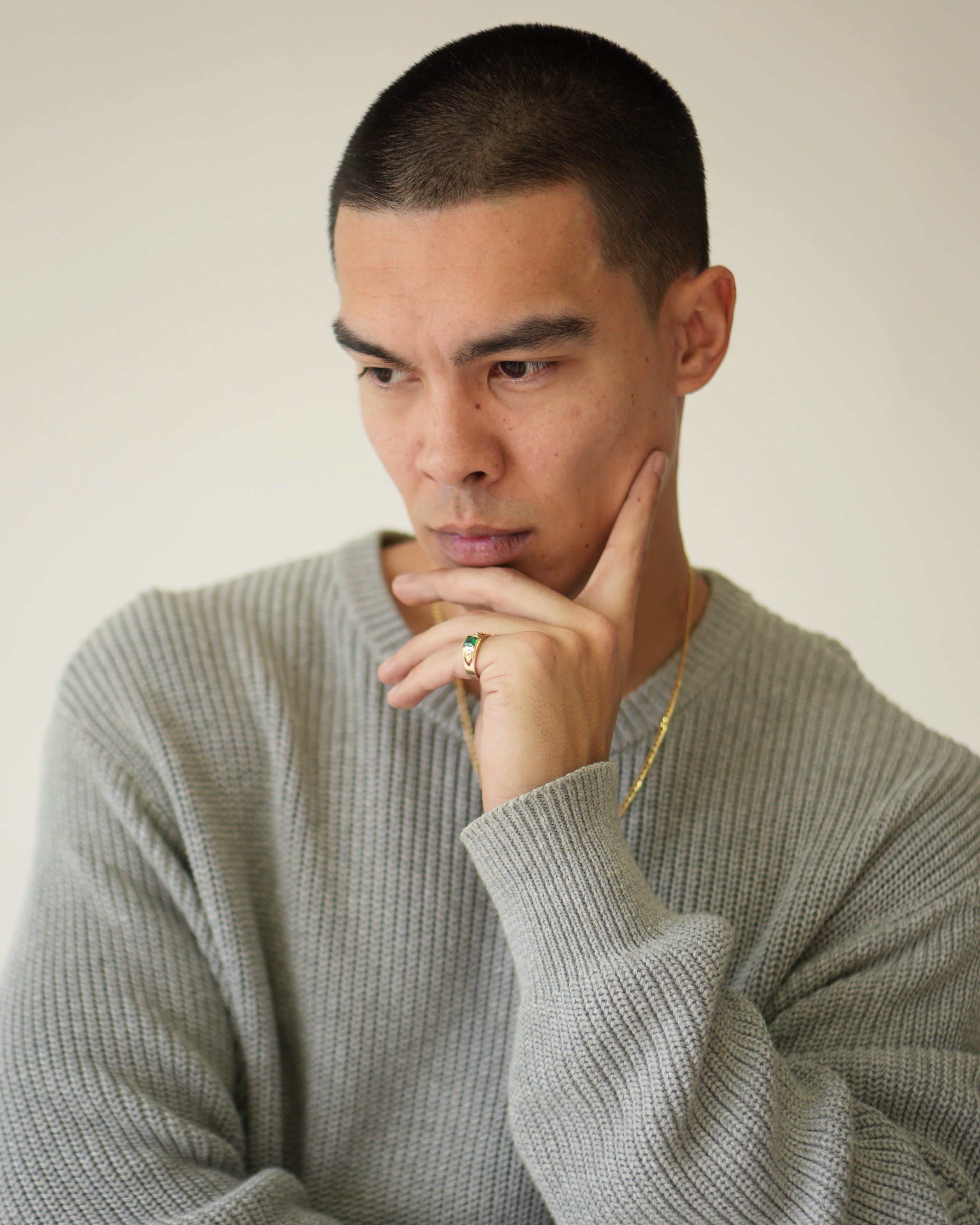Man wearing a gray sweater with a neutral background