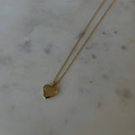 photo of a gold heat locket necklace on top of a marble table