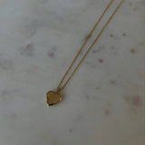 photo of a gold heat locket necklace on top of a marble table