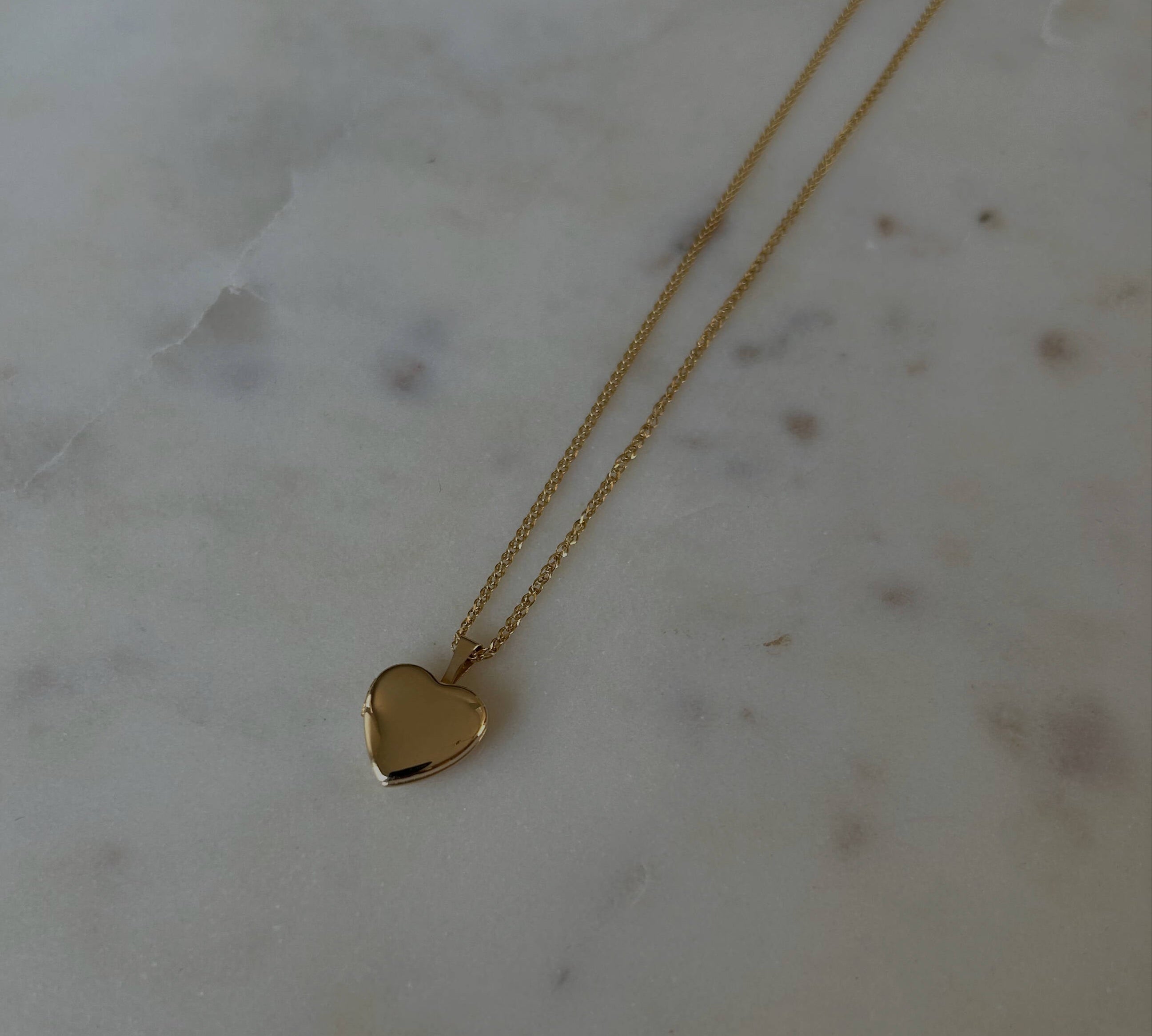 photo of a gold heat locket necklace on top of a marble table