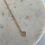image of a 14k gold hear pendant with a triple color singapore chain against a white round marble backdrop
