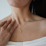 Woman wearing a gold necklace with a small pendant, close-up of neck and chest.