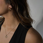 image of a woman wearing gold hoops and a heart necklace
