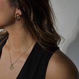 image of a woman wearing gold hoops and a heart necklace
