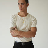 Man wearing a white t-shirt and black pants against a plain background