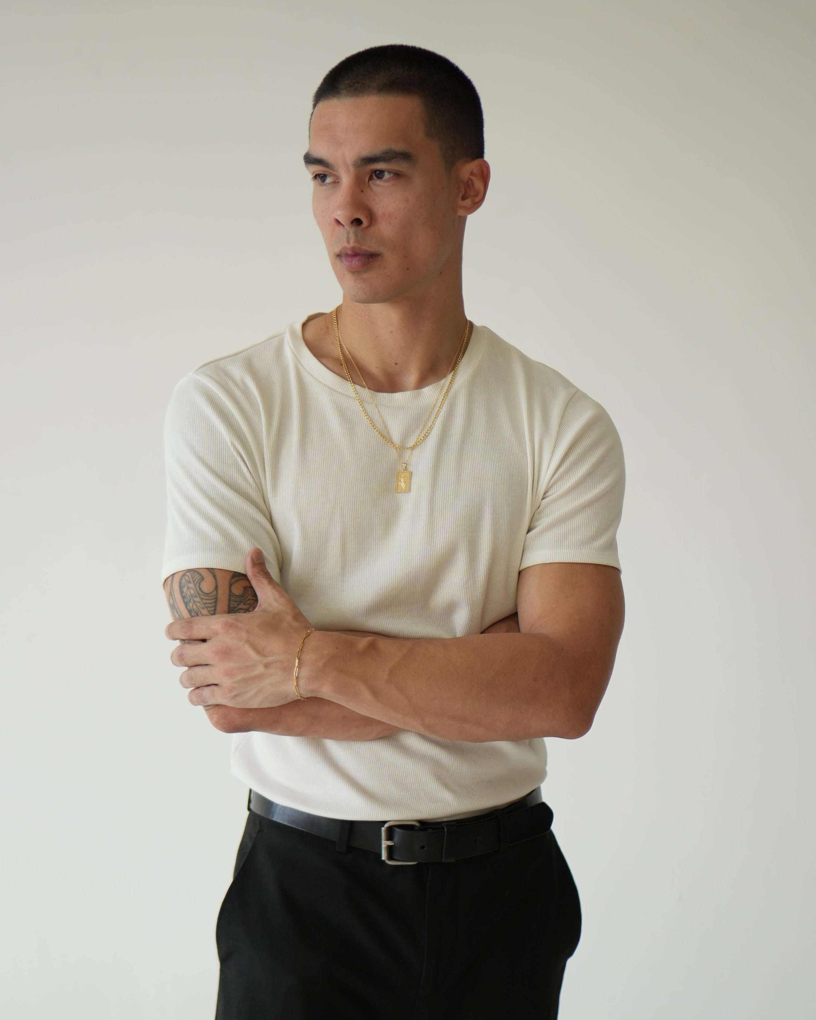 Man wearing a white t-shirt and black pants against a plain background