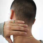 Person wearing a gold necklace with a plain background