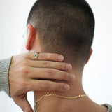 Person wearing a gold necklace with a plain background