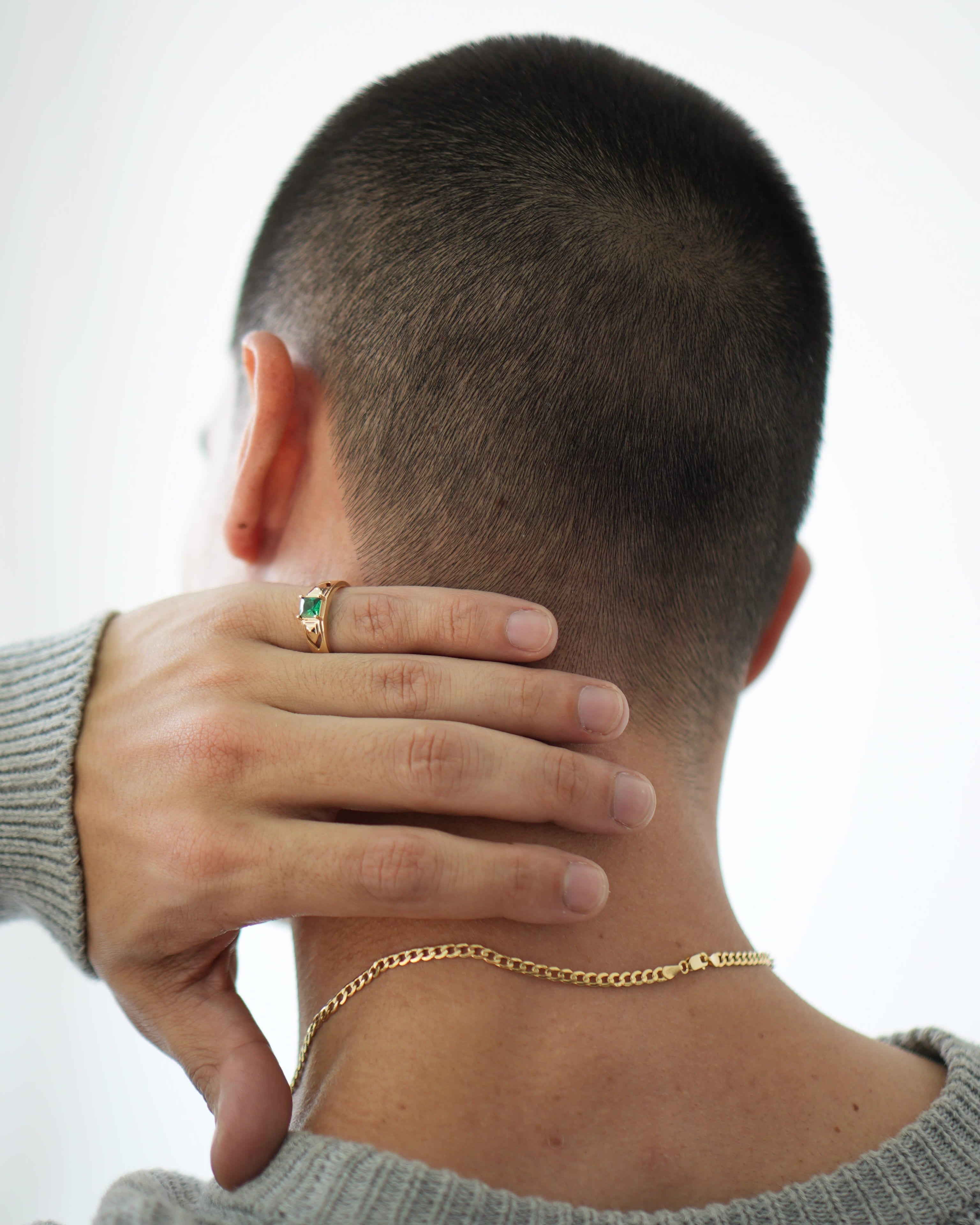 Person wearing a gold necklace with a plain background