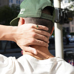 Person wearing a green cap with a blurred city street background