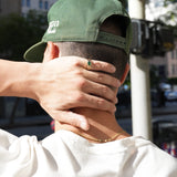 Person wearing a green cap with a blurred city street background