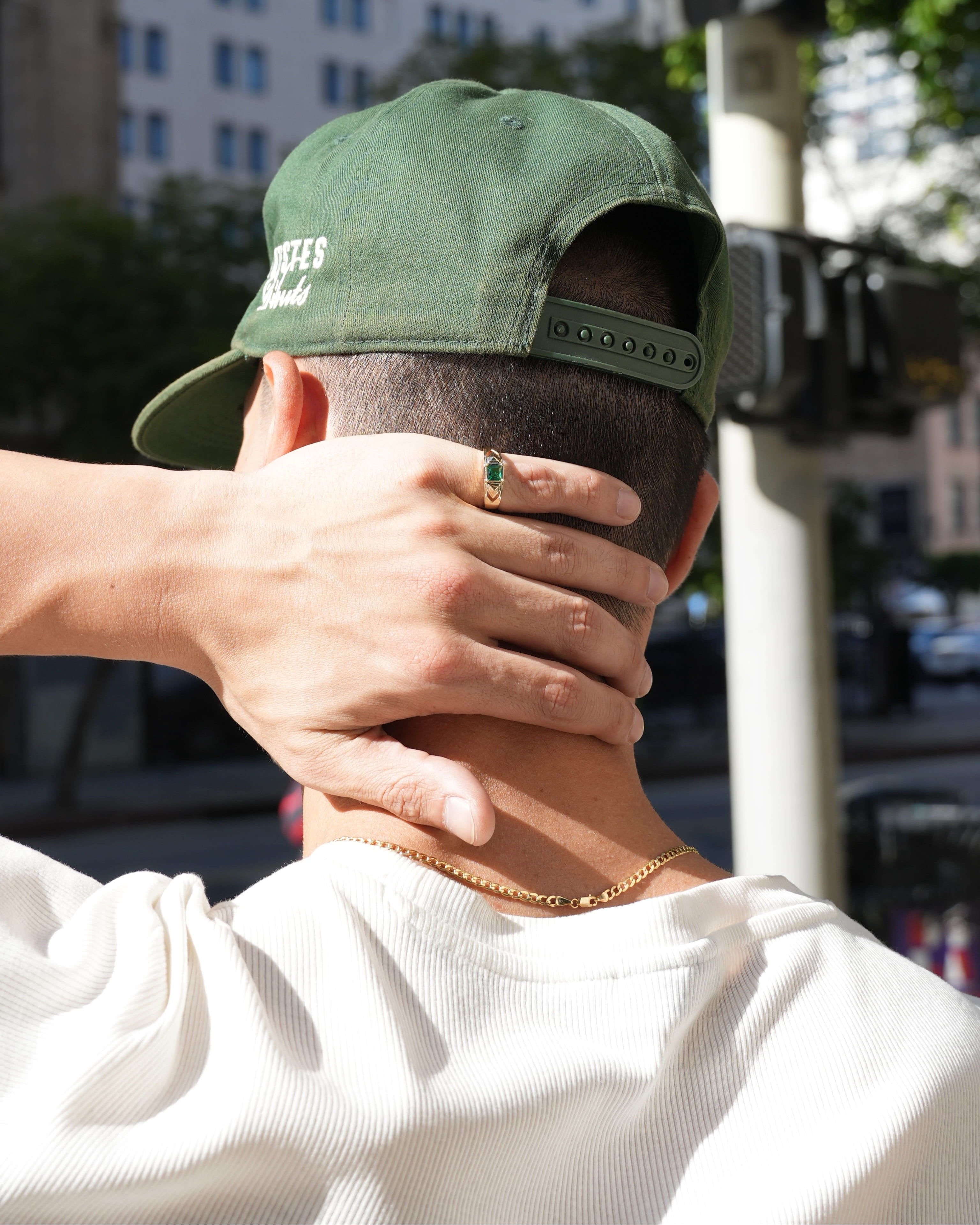 Person wearing a green cap with a blurred city street background