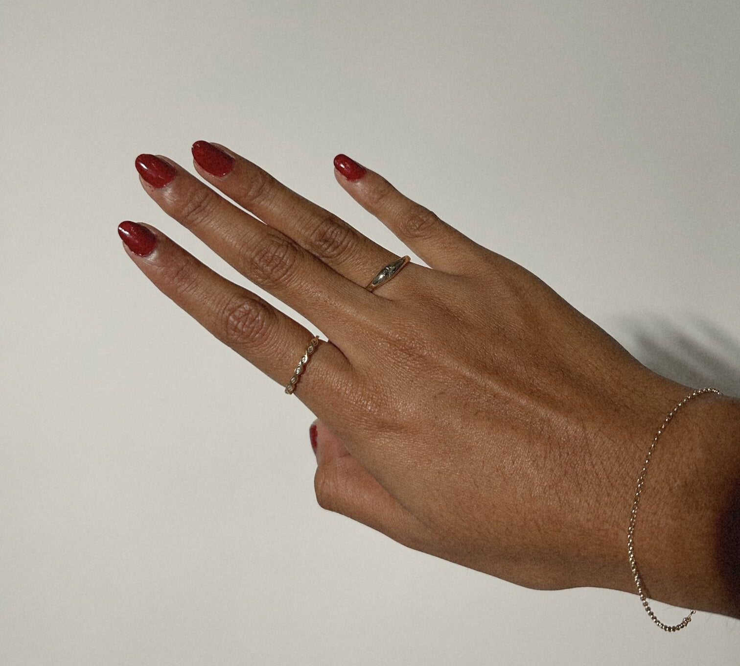 image of a womans hands with two gold rings against a white backdrop