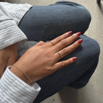 image of a womans hands on her jeans with a gold bracelet and two gold rings