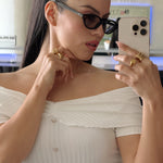 Woman in a white off-shoulder top taking a mirror selfie.
