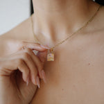 Necklace with a small square pendant worn by a person