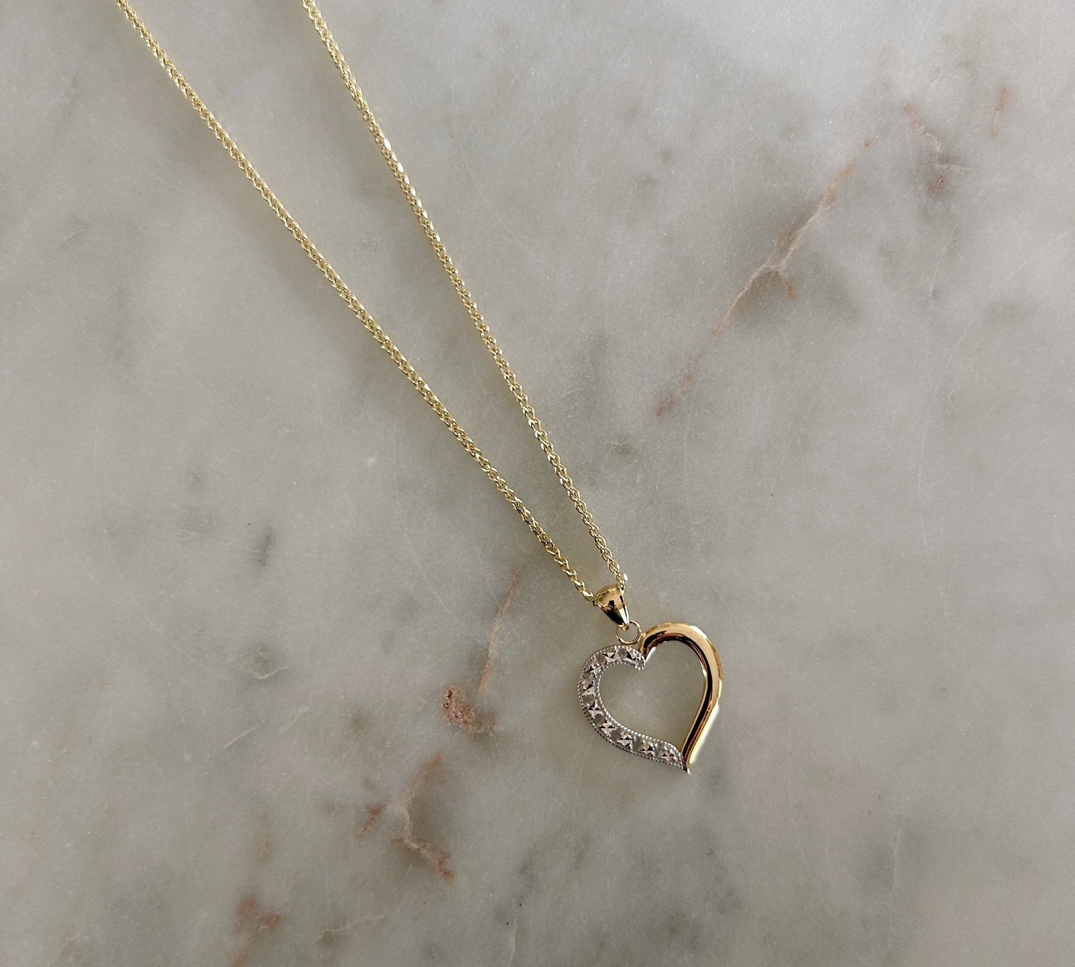 image of a two tone heart pendant against a marble table