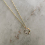 image of a two tone heart pendant against a marble table