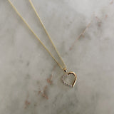 image of a two tone heart pendant against a marble table