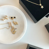 Gold earrings on a white dish with black jewelry boxes in the background