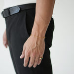 Person wearing a gold bracelet and ring on a plain background