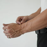 Person wearing a gold bracelet on a plain background