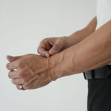 Person wearing a gold bracelet on a plain background