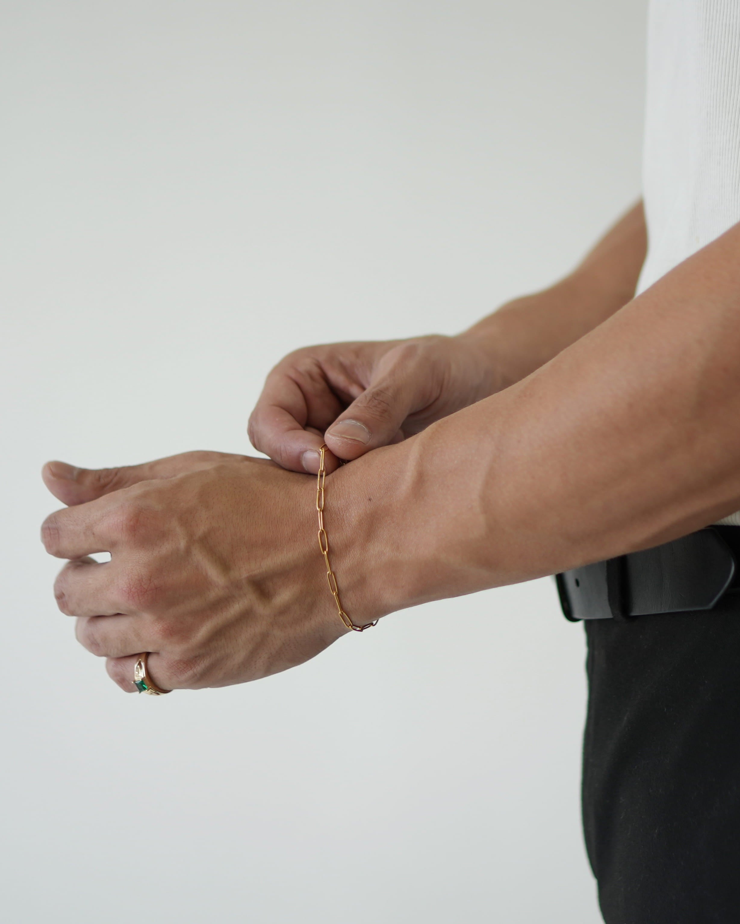 Person wearing a gold bracelet on a plain background